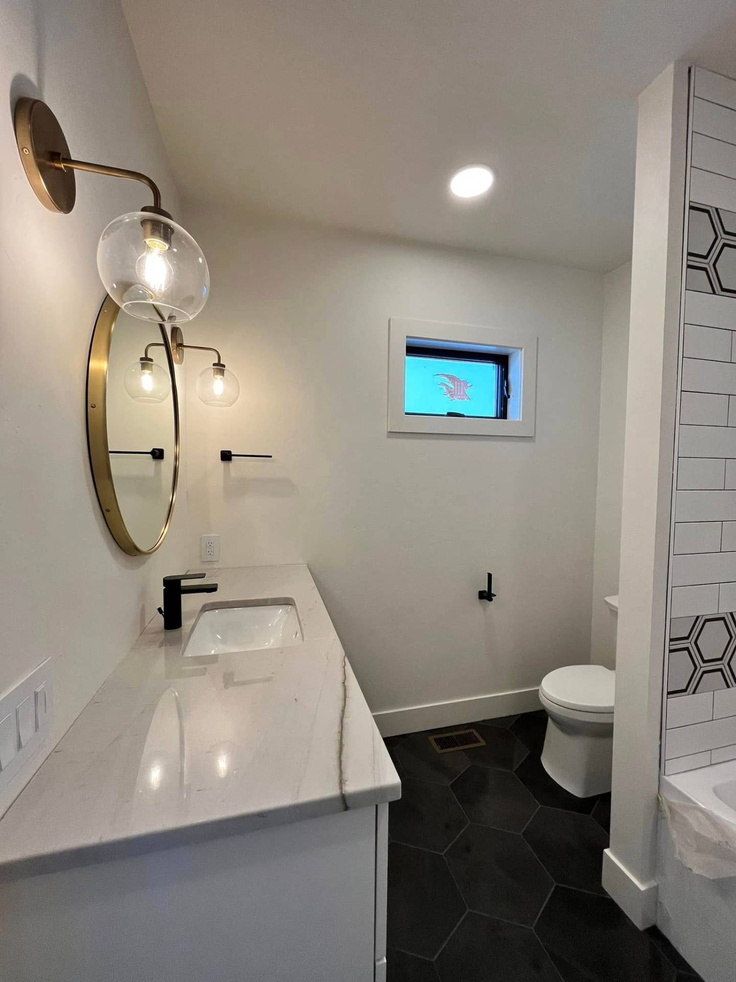 Finished bathroom with crisp white walls, brass fixtures, and hex tile floor by Treeline Painting