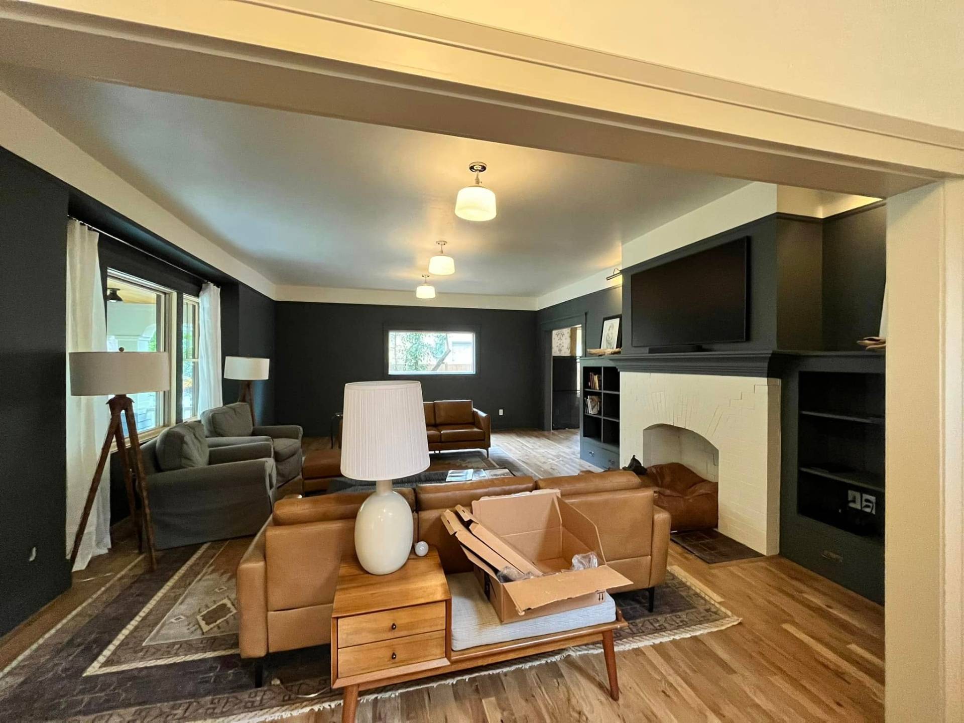 Open living room with deep green walls and cream trim by Treeline Painting