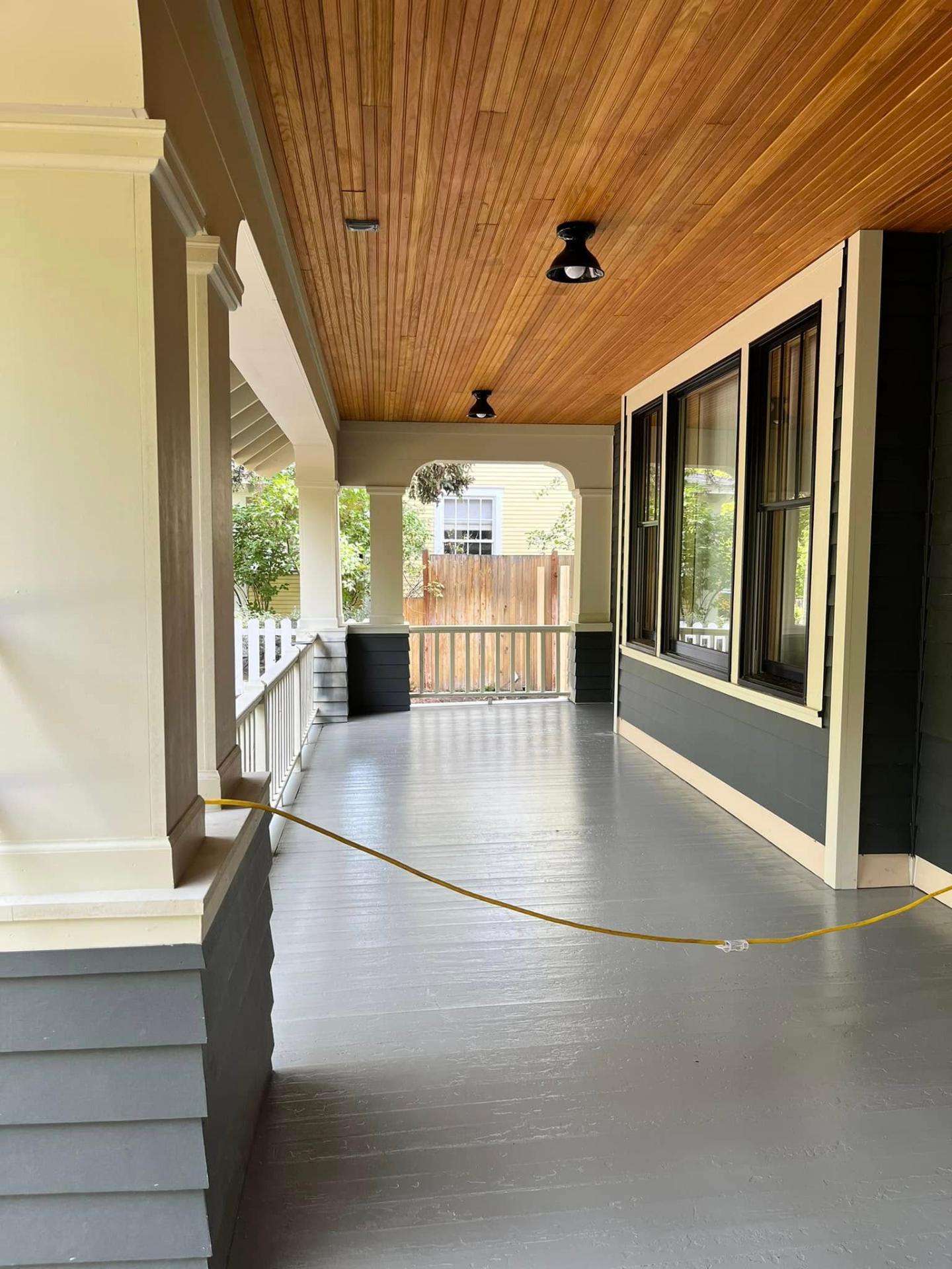 Wraparound craftsman porch with stained wood ceiling and gray painted deck by Treeline Painting