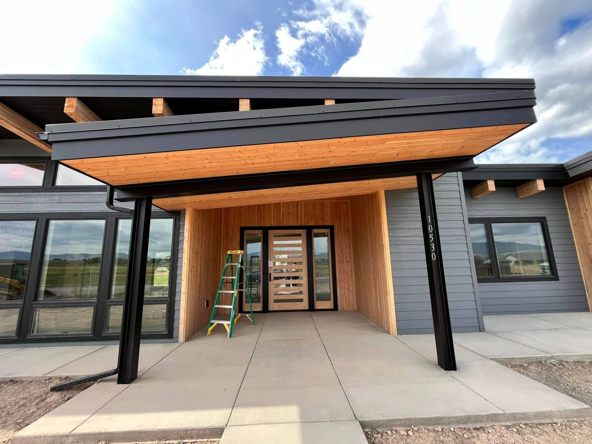 Modern Montana home entry with cedar soffit and dark siding painted by Treeline Painting